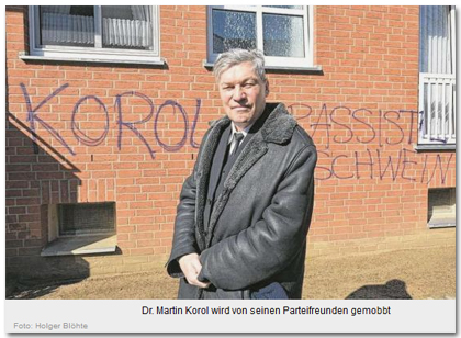 [Das Foto zeigt Martin Korol vor der beschmierten Hauswand. Die Beschriftung lautet:] Dr. Martin Korol wird von seinen Parteifreunden gemobbt